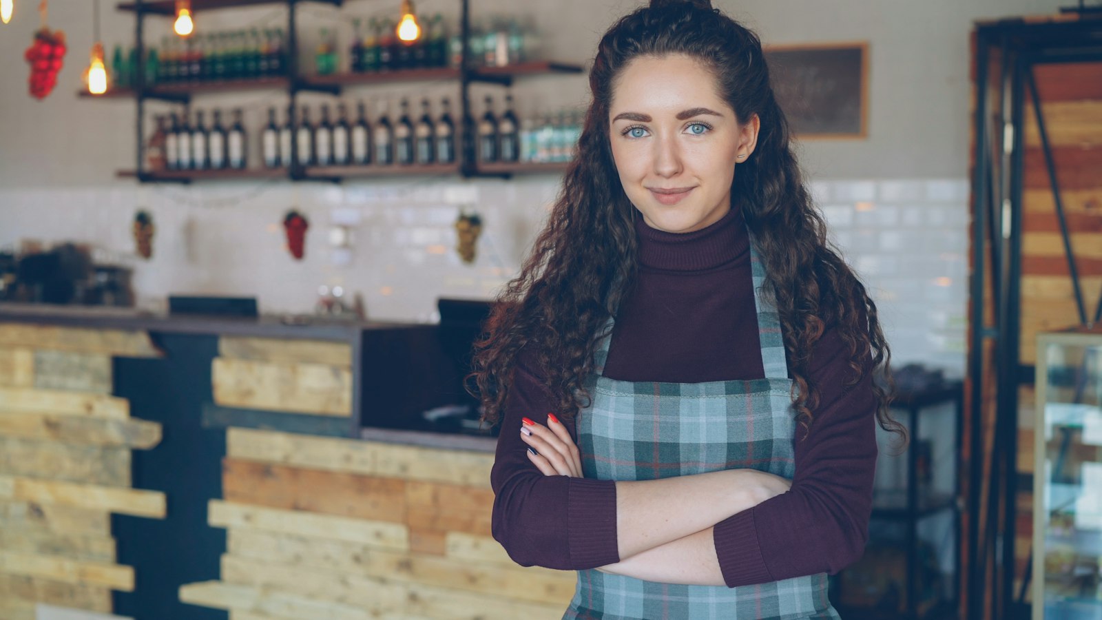 Ondernemer staat met gekruiste armen in haar eigen koffiezaak